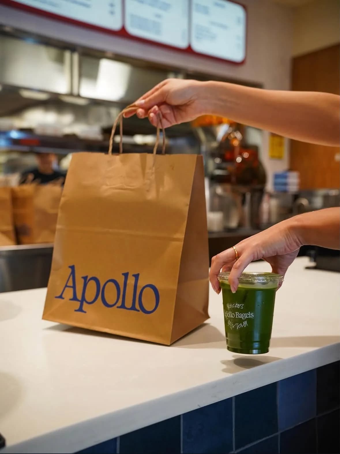 Apollo Bagels — a bag and a matcha handed over the counter